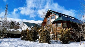 Uma cabana de tronco com uma janela grande e paisagem coberta de neve.