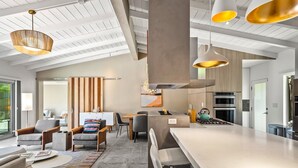 Een moderne keuken met een centraal eiland, een eethoek met stoelen en een zithoek met banken en een salontafel.