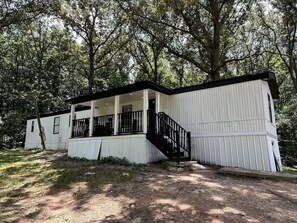 A single-story mobile home with a porch, a staircase, and a fenced yard. - Modern 2 bed Home 10 mins from Dtown Gainesville (Gainesville)