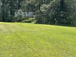 Une zone herbeuse avec un petit bâtiment en arrière-plan.