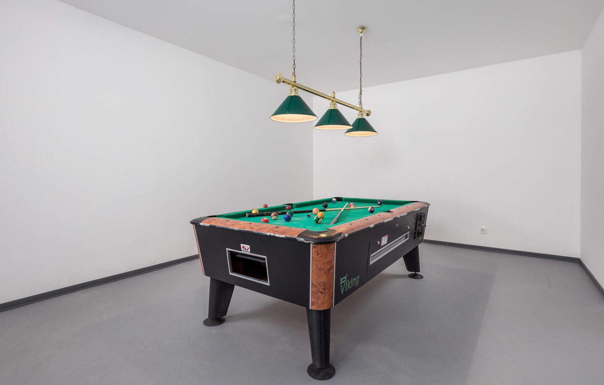 A foosball table in a room with white walls and a grey floor.