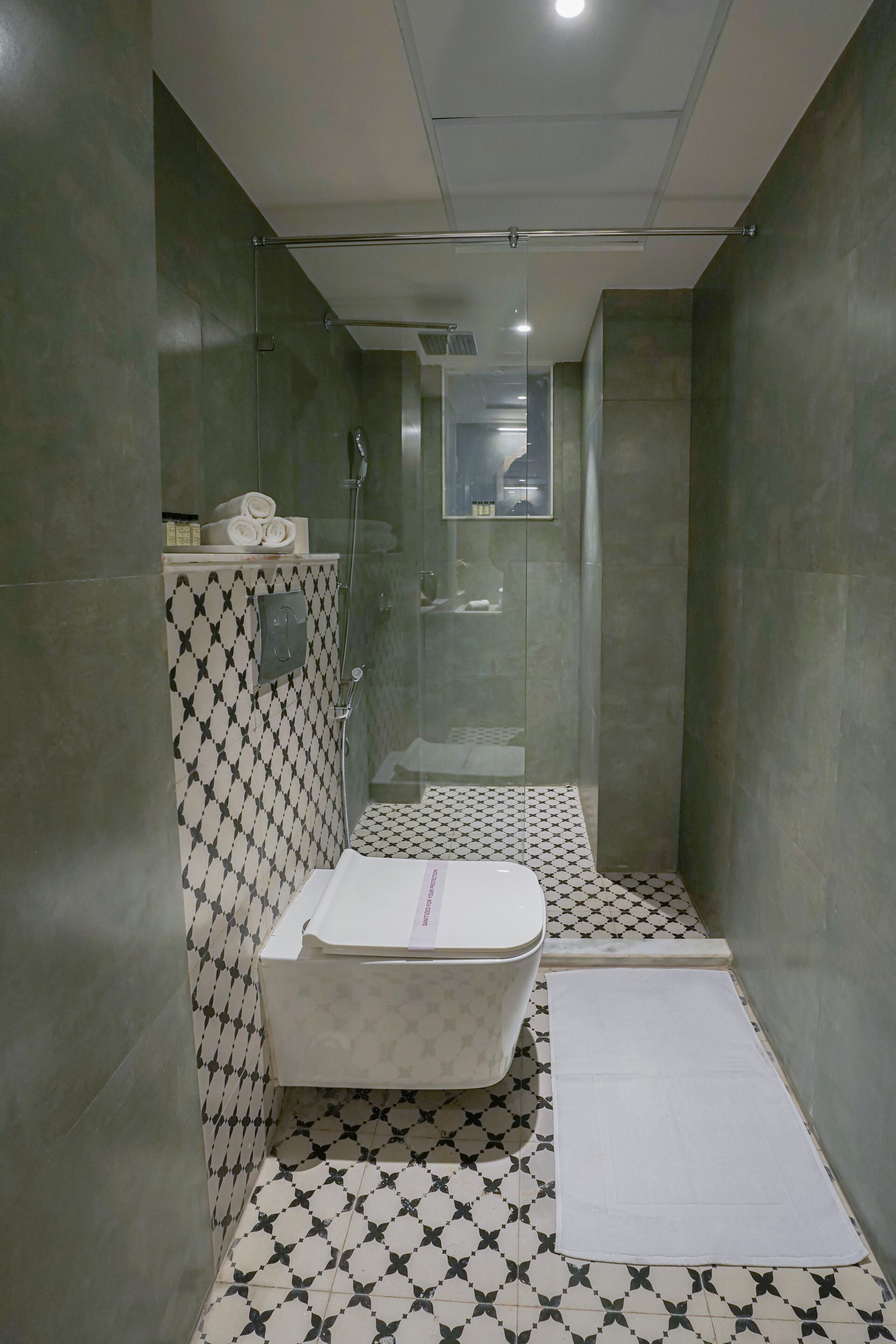 A modern bathroom with a glass-enclosed shower, a bathtub, and patterned floor tiles.