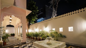 A checkered floor, a fountain, potted plants, and a building with a blue-lit entrance. - Dev Mahal - A Boutique Heritage Hotel (Jaipur)