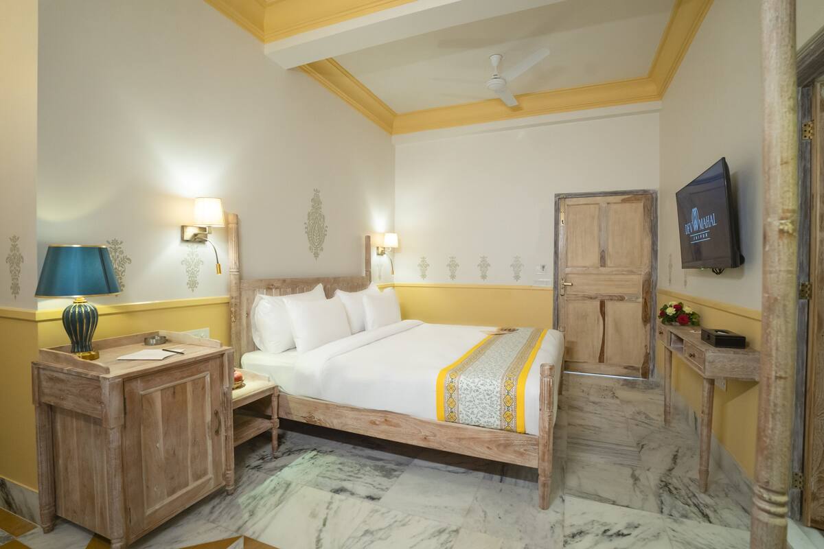 A bedroom with a wooden bed, two bedside lamps, a television, and a wooden wardrobe.