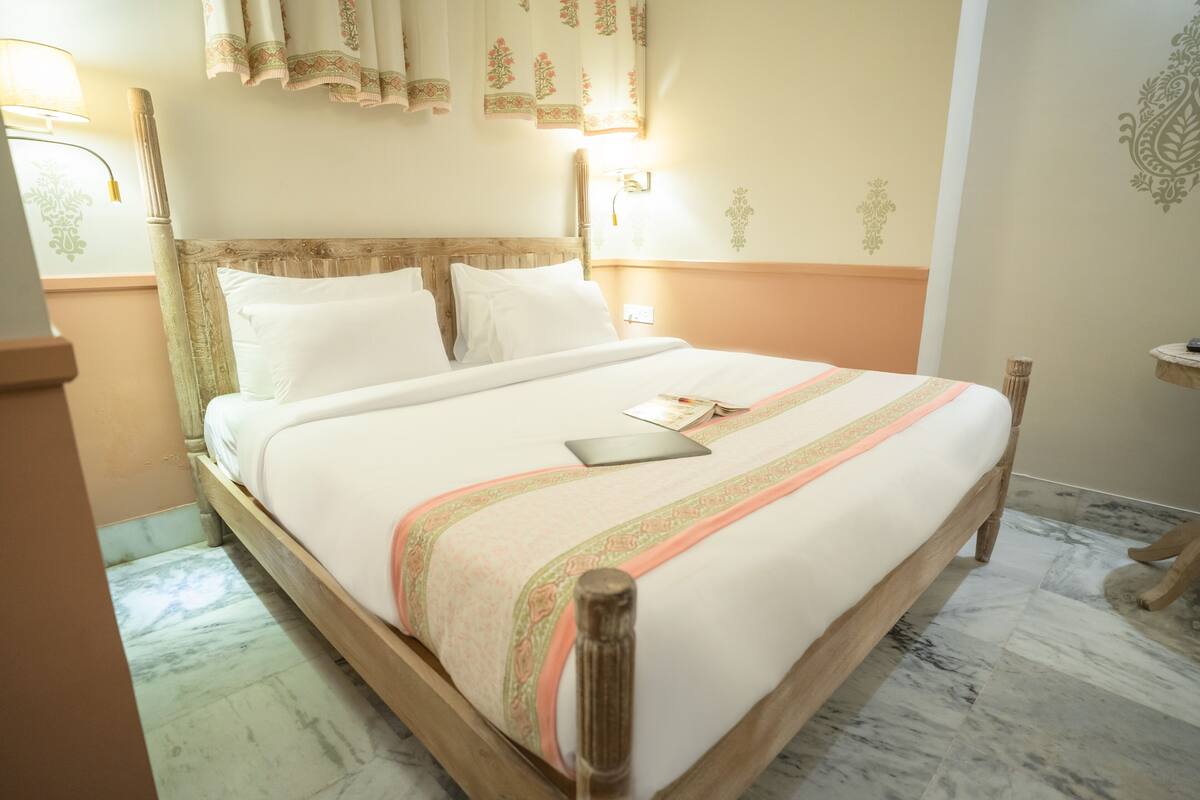 A neatly made bed with a wooden headboard, a bedside lamp, and a small table with a book.
