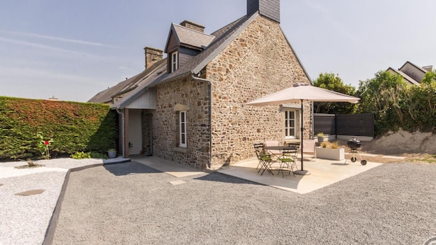 A stone house with a patio, outdoor seating, and a barbecue area. - Charming stone house with courtyard and terrace in Créances (Créances)