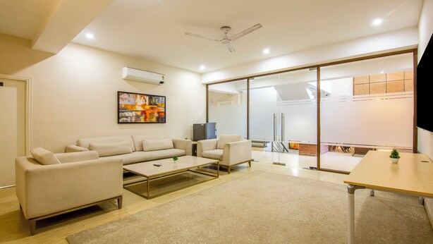 A modern living room with a sofa set, a coffee table, and a TV. - Treebo Jass Hospitality Services - Sec 53 (Gurugram)