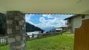 Un pilier de pierre, une porte en bois et une vue sur un paysage montagneux avec des bâtiments.