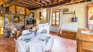 A rustic dining area with a stone fireplace, wooden beams, and a tiled floor. - Charming stone house with garden, ideal for couple (Gavray-sur-Sienne)