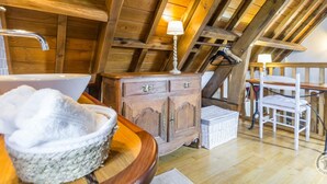 A rustic wooden room with a wooden cabinet, a white chair, and a wooden table. - Charming stone house with garden, ideal for couple (Gavray-sur-Sienne)