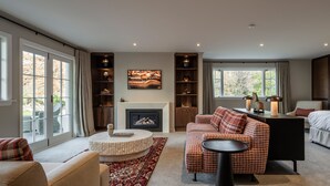 Ein geräumiges Wohnzimmer mit Kamin, einer Sofagarnitur, einem Couchtisch und einem Bücherregal.