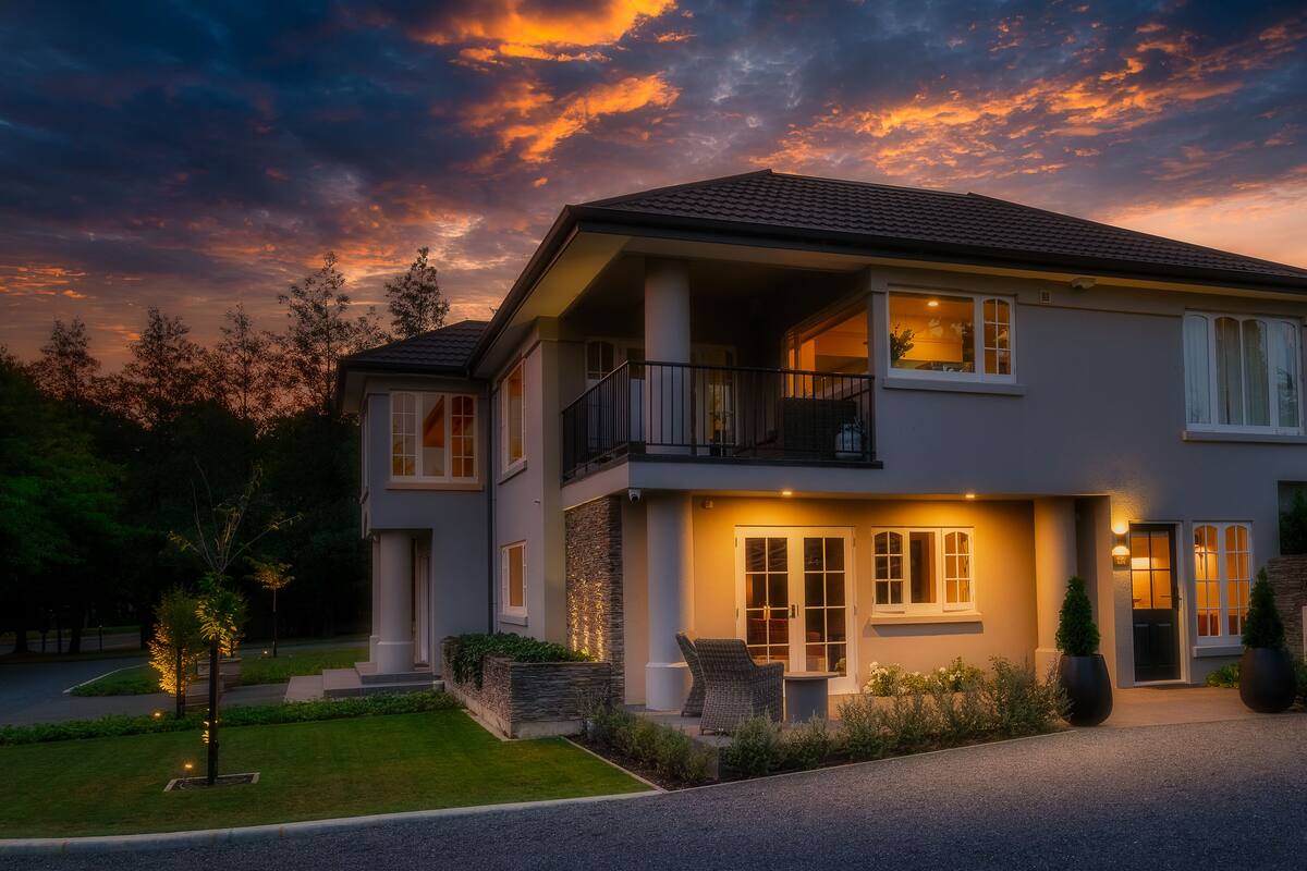 A two-story house with a balcony, large windows, and a well-lit entrance.