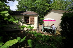 Enjoy a tranquil retreat in this serene outdoor setting, surrounded by lush greenery and a charming house with a cozy dining area.