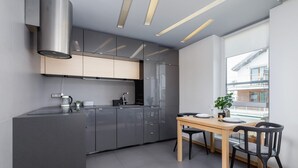 Una cocina moderna con armarios grises, una campana extractora de acero inoxidable y un comedor con mesa y sillas de madera.