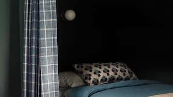 A small, cozy room with a bed, a pillow, and a bedside table.