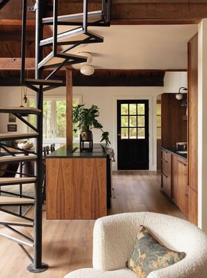Una cocina moderna con armarios de madera, una isla central y una escalera en espiral.