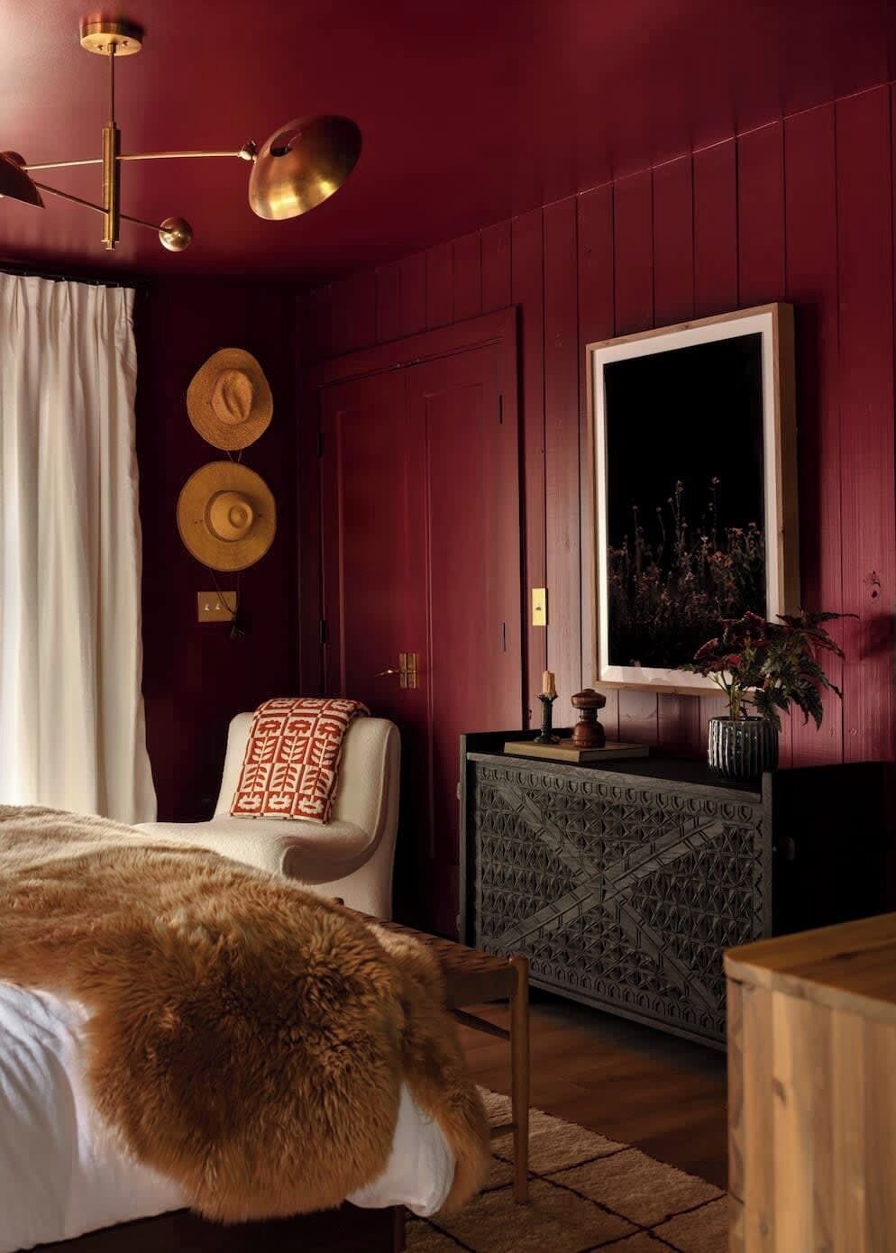 A room with a bed, a chair, a dresser, and a mirror.