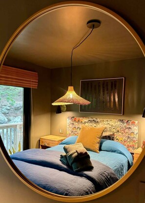 A circular room with a bed, a hanging lamp, and a window with blinds.