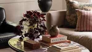 A cozy living room with a round glass coffee table, a black lamp, a sofa, and a window with a view of greenery. - Canyon Grove - Secluded lake retreat (Garfield)