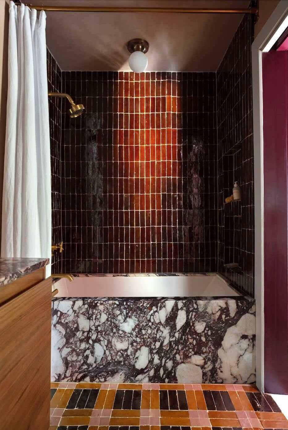 A bathroom with a bathtub, tiled walls, and a marble floor.