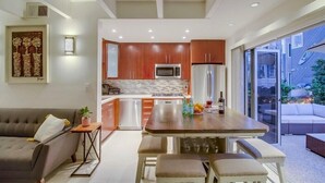 Una cocina moderna con armarios de madera, electrodomésticos de acero inoxidable y una zona de comedor con mesa y bancos.