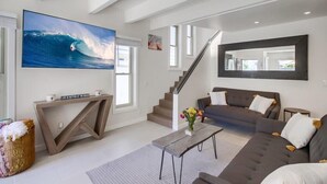 Una sala de estar moderna con un televisor grande, un sofá, una mesa de centro y una escalera.