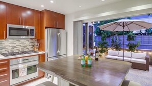 Una cocina moderna con electrodomésticos de acero inoxidable, encimera de madera y un comedor con una sombrilla grande.