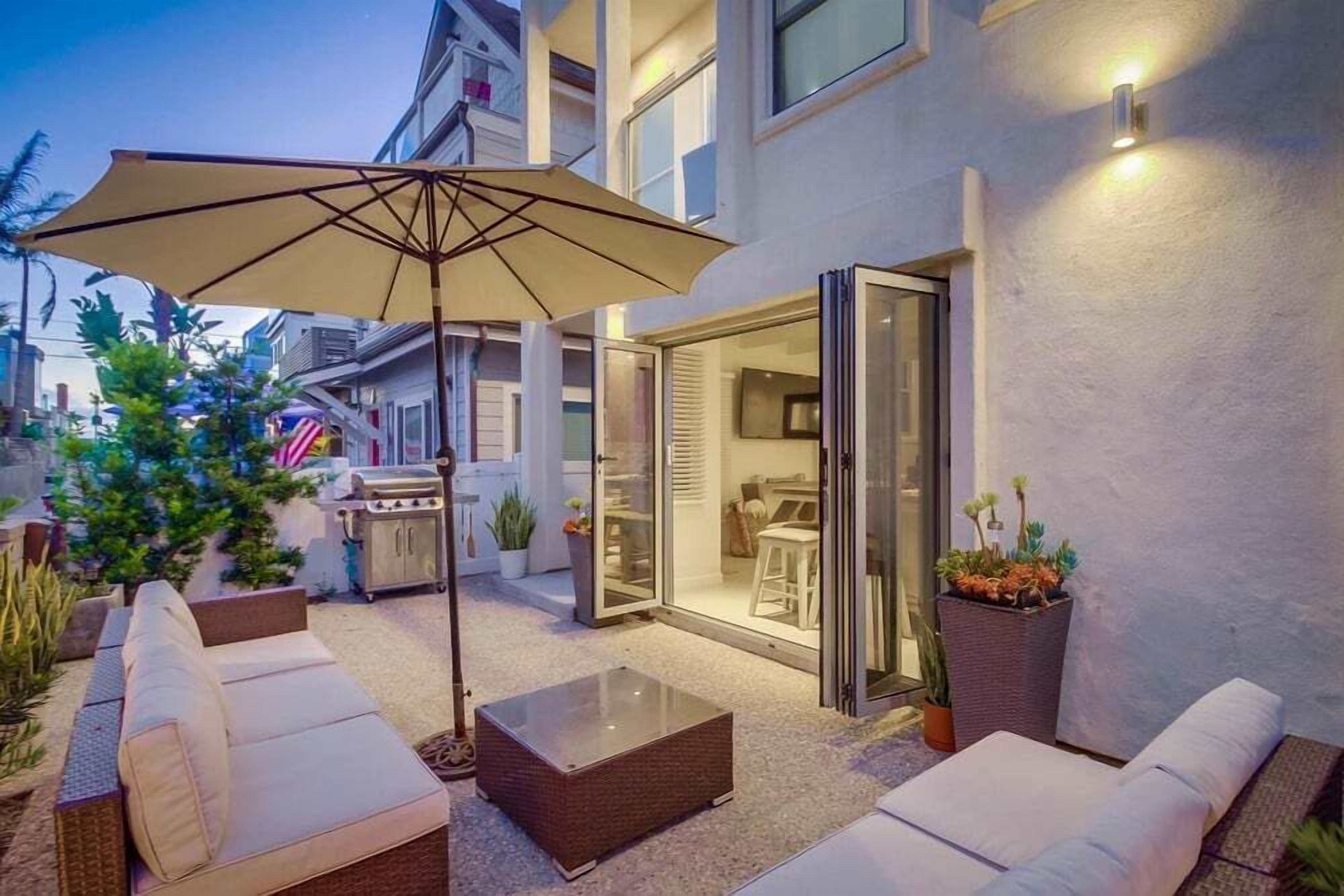 An outdoor patio with a sofa, a glass-top coffee table, and a large umbrella.