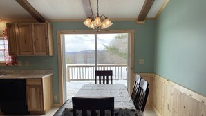 Una cocina con armarios de madera, una mesa de comedor con sillas y vistas a una terraza exterior a través de un ventanal.