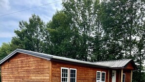 Una cabaña de madera con un porche y un letrero que dice "HILTOP COTTAGE".