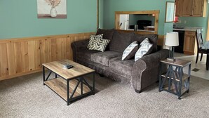 Una sala de estar con sofá, mesa de centro y lámpara.