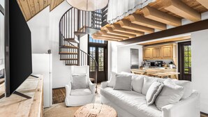 Un intérieur moderne avec un escalier, des meubles blancs et un coin cuisine.