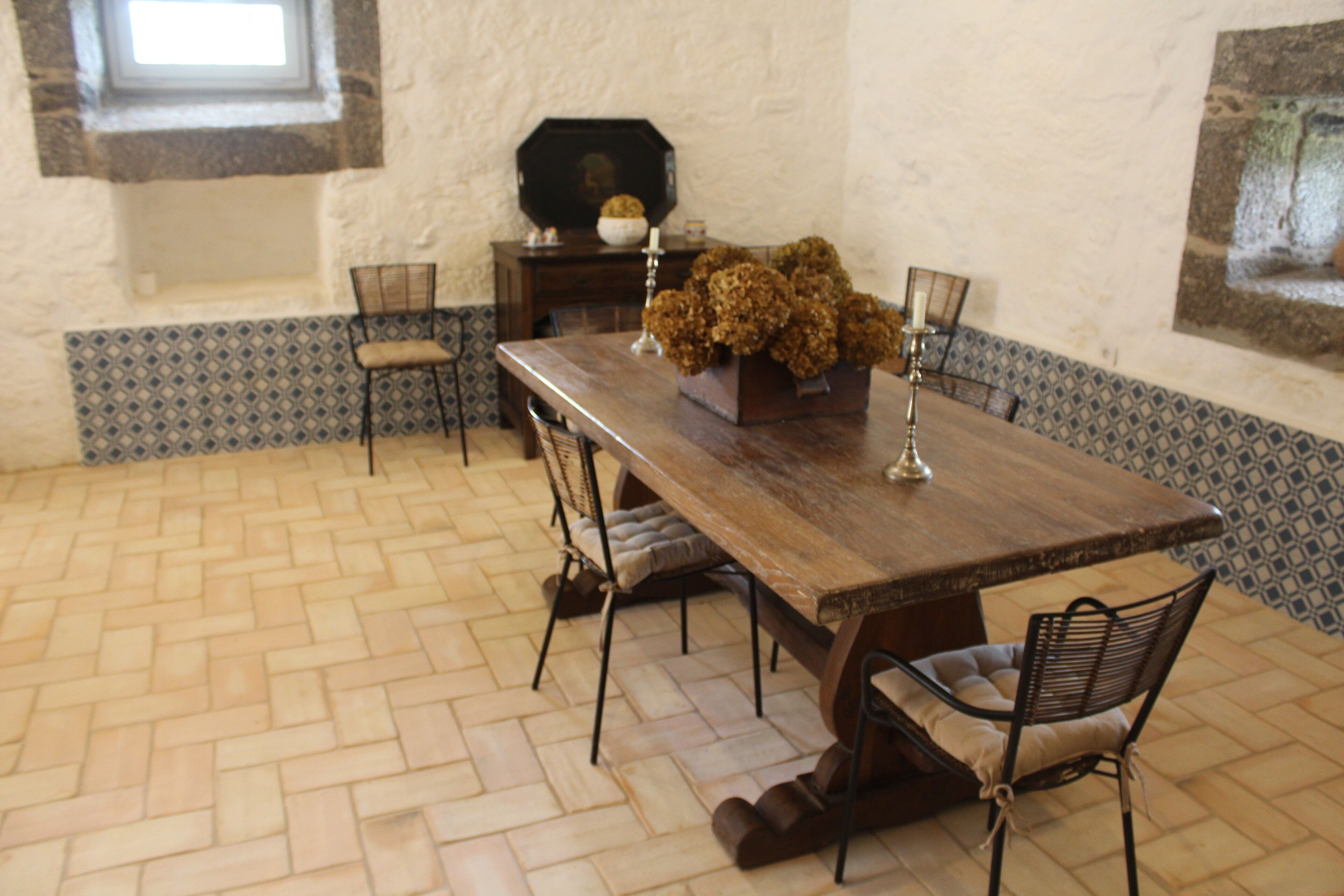 A dining area with a wooden table, four chairs, and a decorative centerpiece.