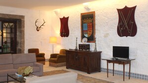 Ein Wohnzimmer mit einer Couch, Sesseln, einem Couchtisch, einem Fernseher und Wanddekorationen, darunter Geweihe und Schilder.