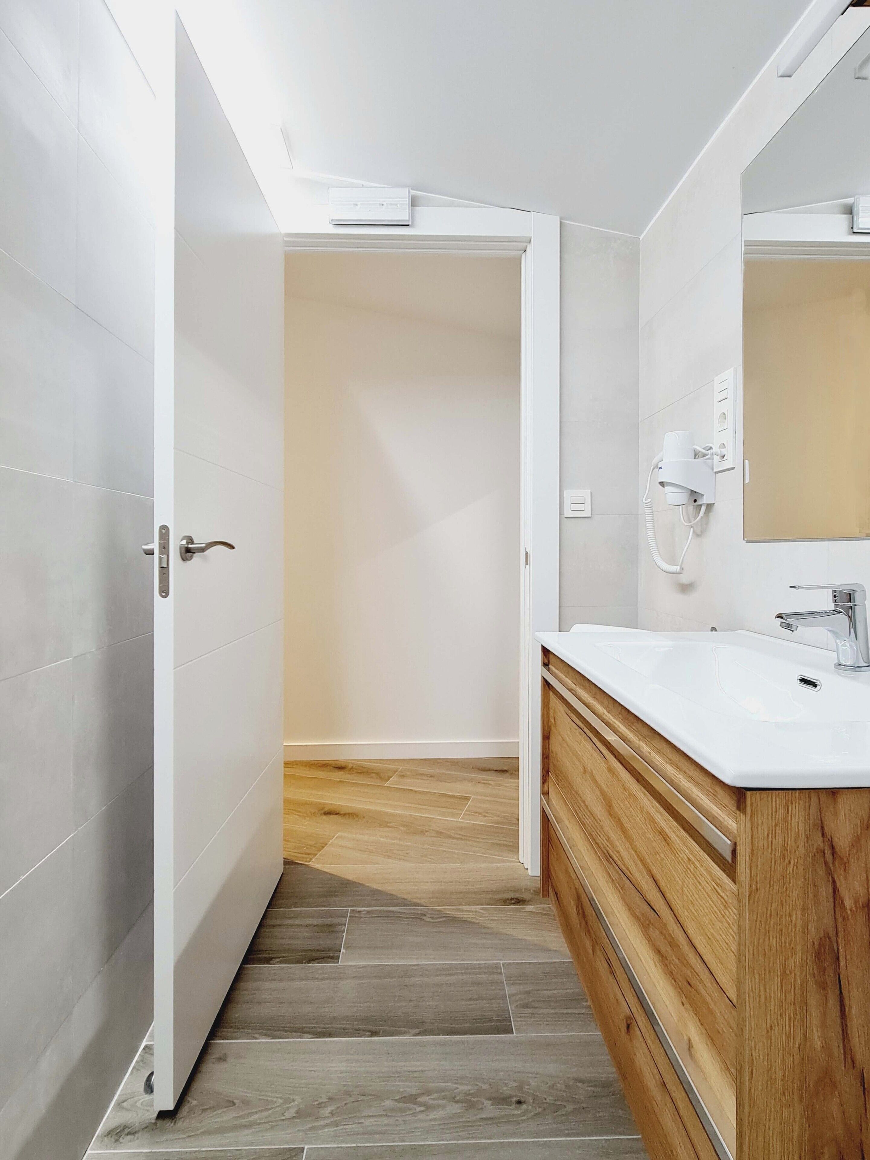 Un baño moderno con tocador de madera, un espejo grande y un lavabo blanco.