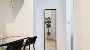 Een moderne eethoek met een glazen tafel, zwarte stoelen en een potplant op een plank.