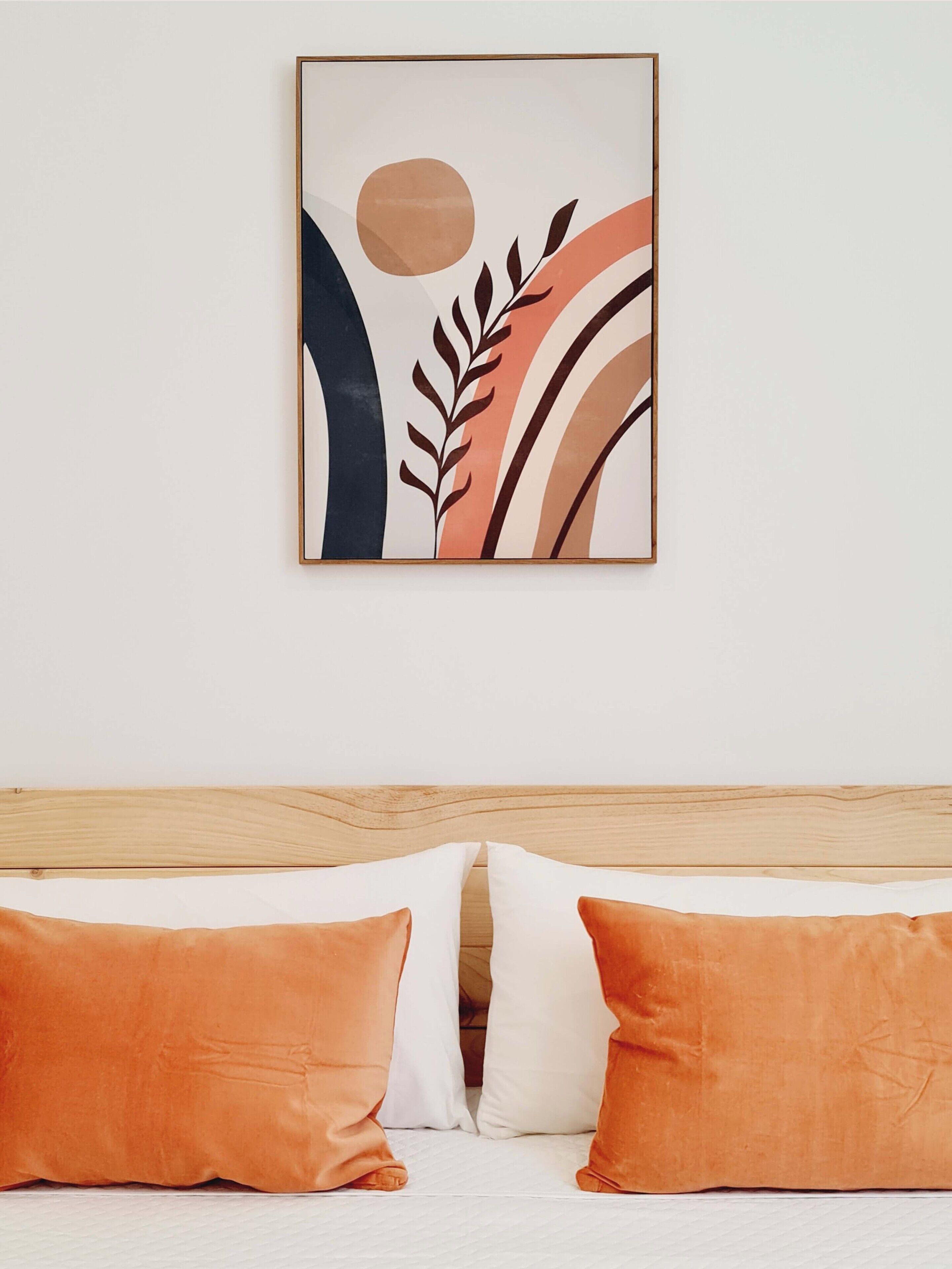 A bedroom with a bed, two pillows, and a wall-mounted abstract artwork.