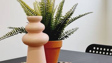 Un tavolo con un sottopiattino intrecciato, un piccolo vaso di felce e un vaso di fiori.