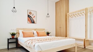 Een moderne slaapkamer met een houten bed, twee nachtkastjes met planten, een garderobe en een hanglamp.
