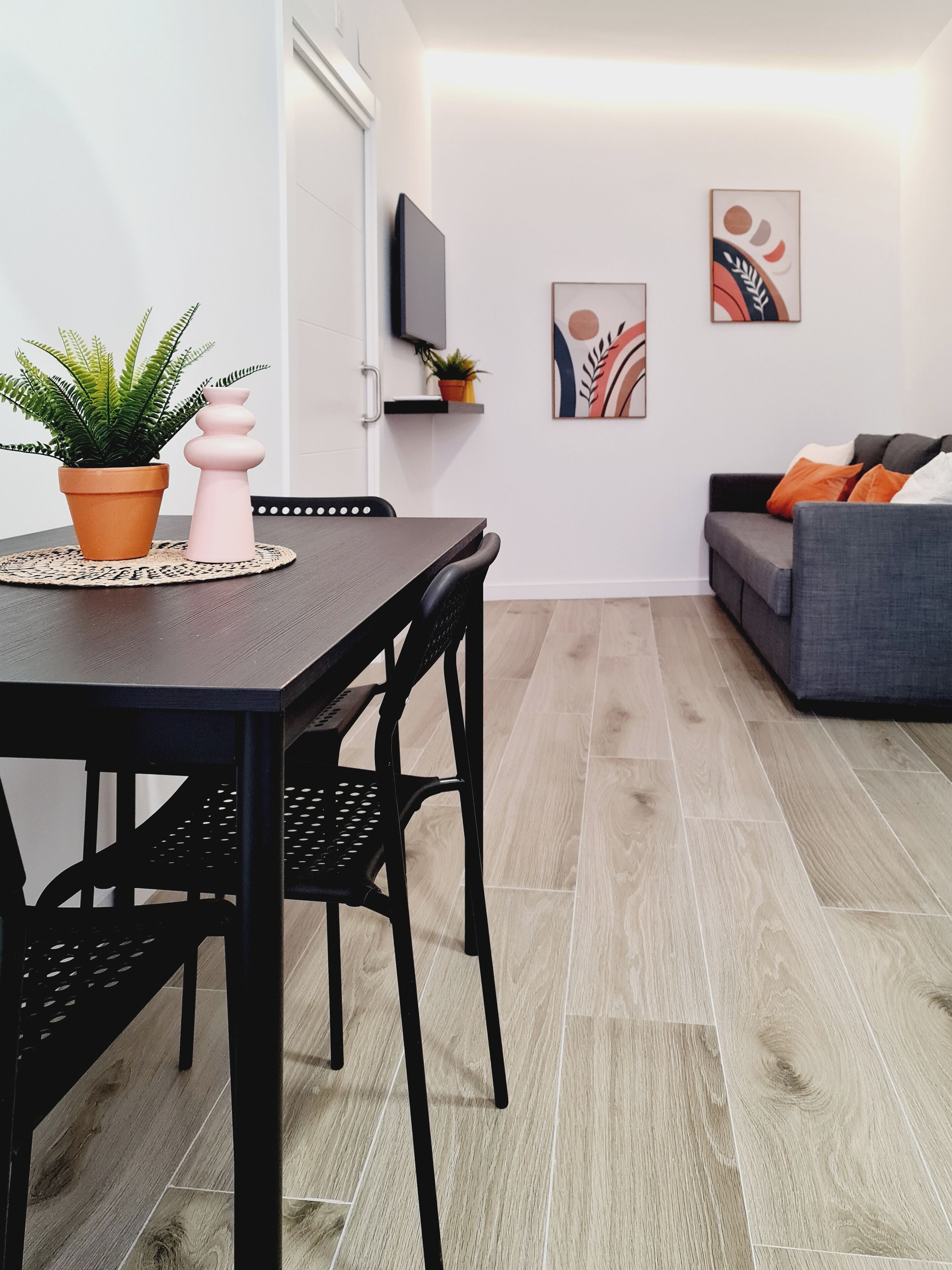 Un salon moderne comprenant une table à manger, des chaises, un canapé et des objets de décoration.
