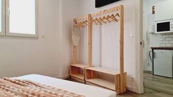 Un dormitorio con cama, un armario de madera, televisor y kitchenette.