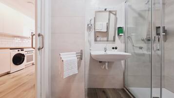 A modern bathroom with a glass shower enclosure, a sink with a mirror, and a towel rack.