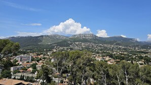 A town with a mix of residential buildings and a prominent mountain range in the background. - Appartement Cosy 4 Personnes (Toulon)
