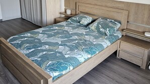 A bedroom with a wooden bed, a nightstand, a bedside table, and a wardrobe. - Appartement Cosy 4 Personnes (Toulon)