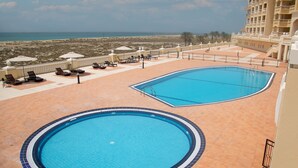Zona d'una piscina al terrat amb dues piscines, gandules i vistes a la platja.