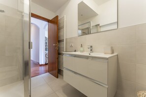 A modern bathroom with a walk-in shower, a large mirror, and a white vanity with a sink and towel rack. - Un minuto dal mare (Bogliasco)