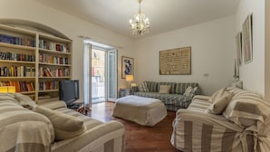 A living room with striped sofas, a bookshelf, a television, and a chandelier. - Un minuto dal mare (Bogliasco)