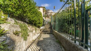 A concrete staircase with metal railings, surrounded by greenery and a stone wall. - Un minuto dal mare (Bogliasco)