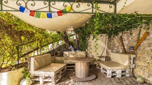 An outdoor seating area with a round table and two sofas, surrounded by greenery and a stone wall. - Un minuto dal mare (Bogliasco)