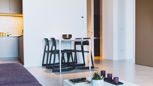 En moderne stue med minimalistisk indretning, med en hvid sofa, et sofabord med dekorative genstande og et spiseområde med stole og bord.